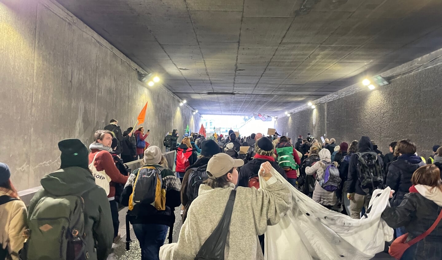 Demonstranten lopen onder de tunnel door.