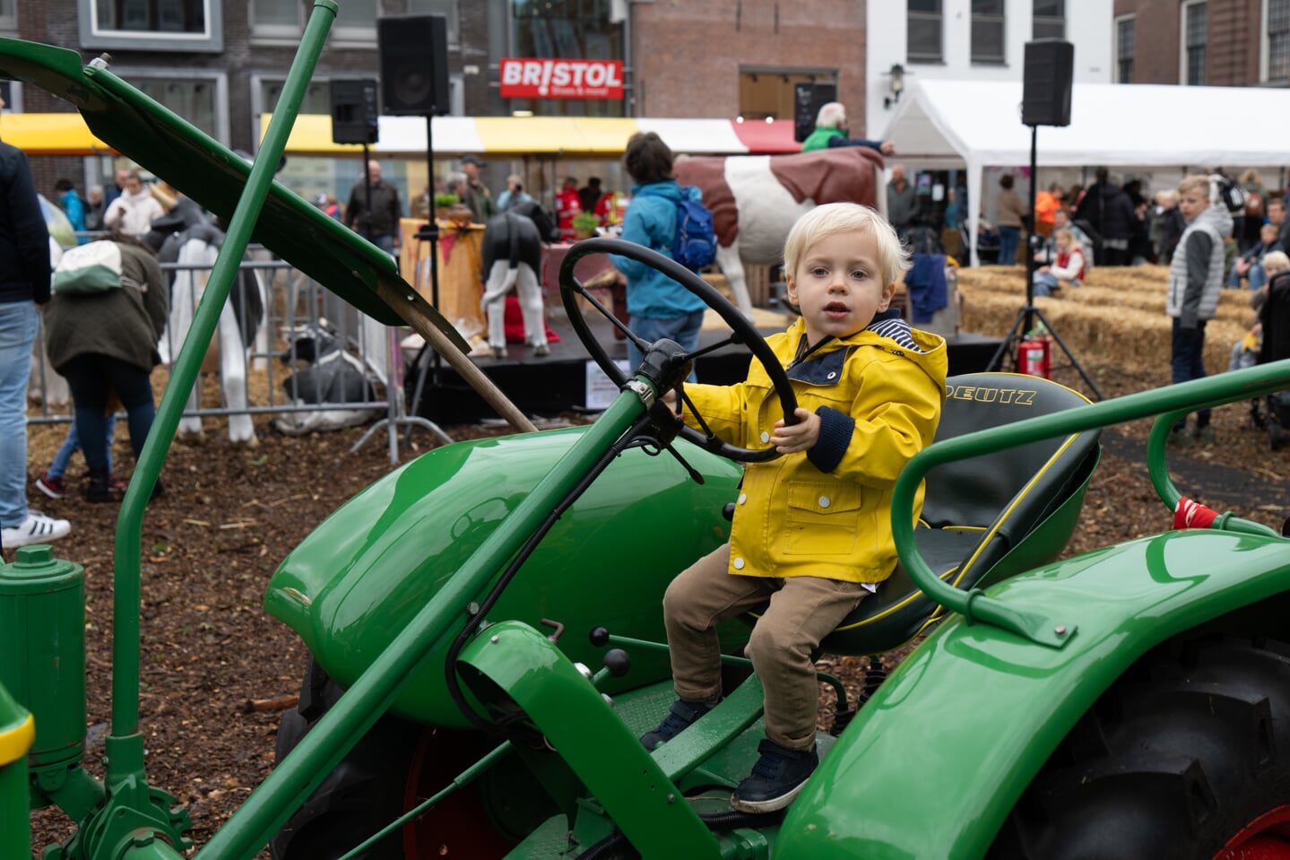 • Een jonge bezoeker van de Koeiemart achter het stuur van een klassieke tractor.