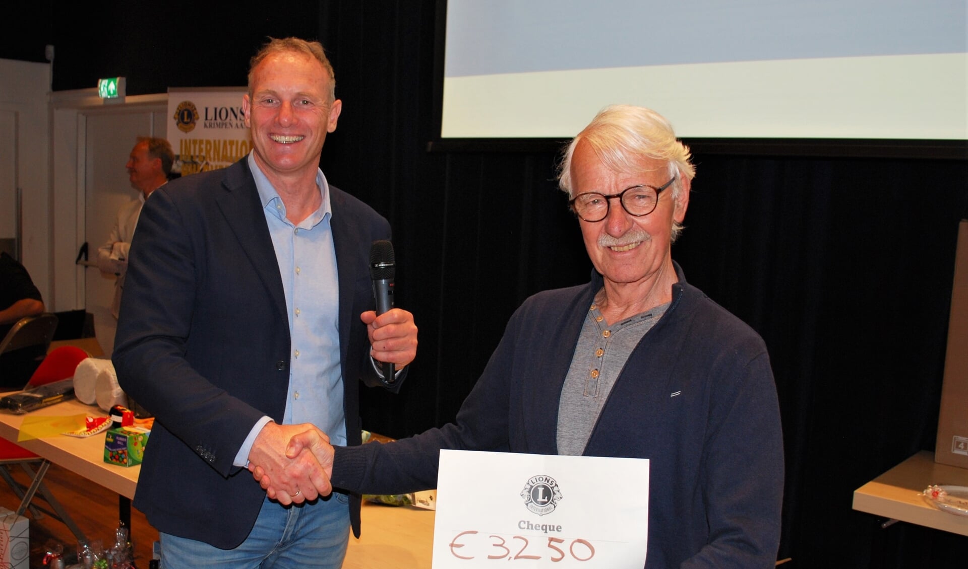 • Kees Burggraaf reikt de cheque uit aan Belbus voorzitter Paul in het Veld.