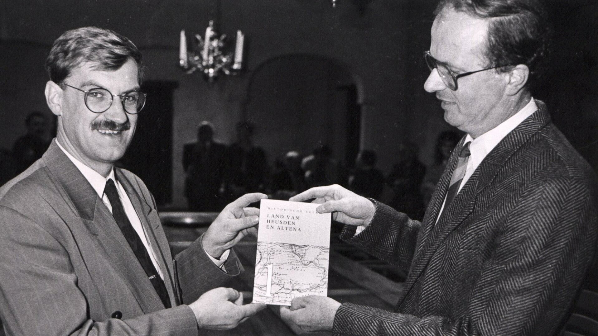 • De uitreiking van het eerste deel van de Historische Reeks Land van Heusden en Altena aan burgemeester Hellegers (links) door voorzitter Cees de Gast in 1990.