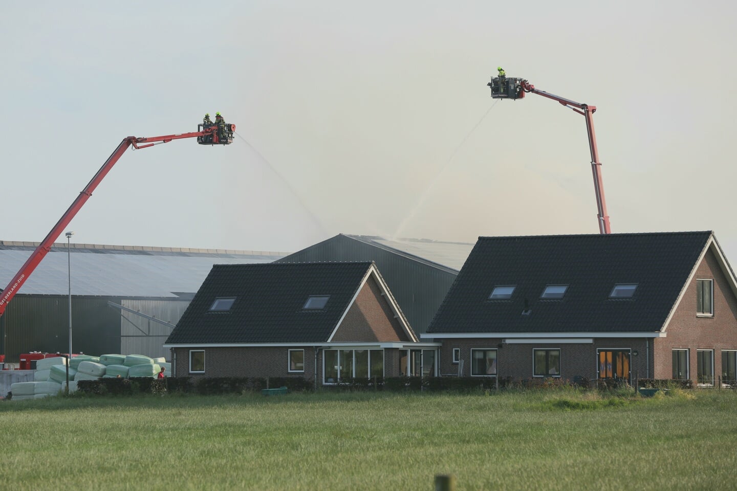 • Brandweerlieden in hoogwerkers bezig met het bestrijden van het vuur.