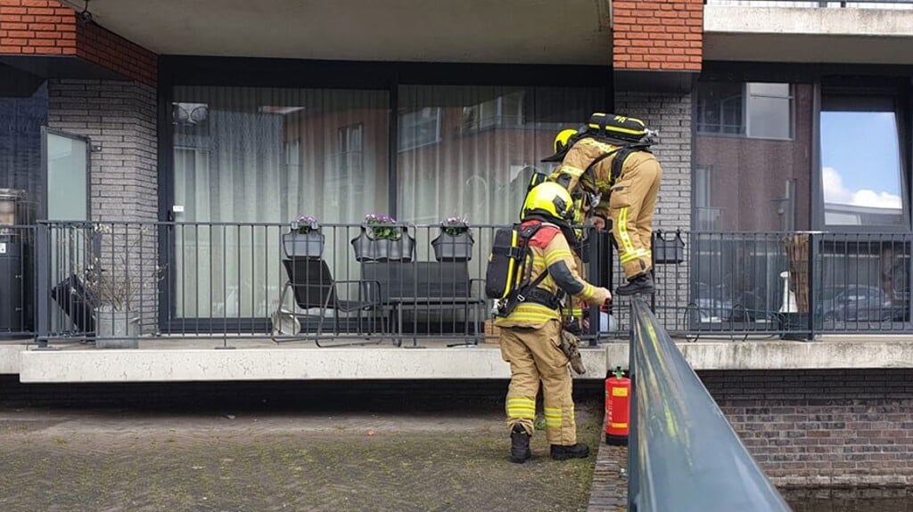 • De brandweer gaat naar binnen in het appartement.