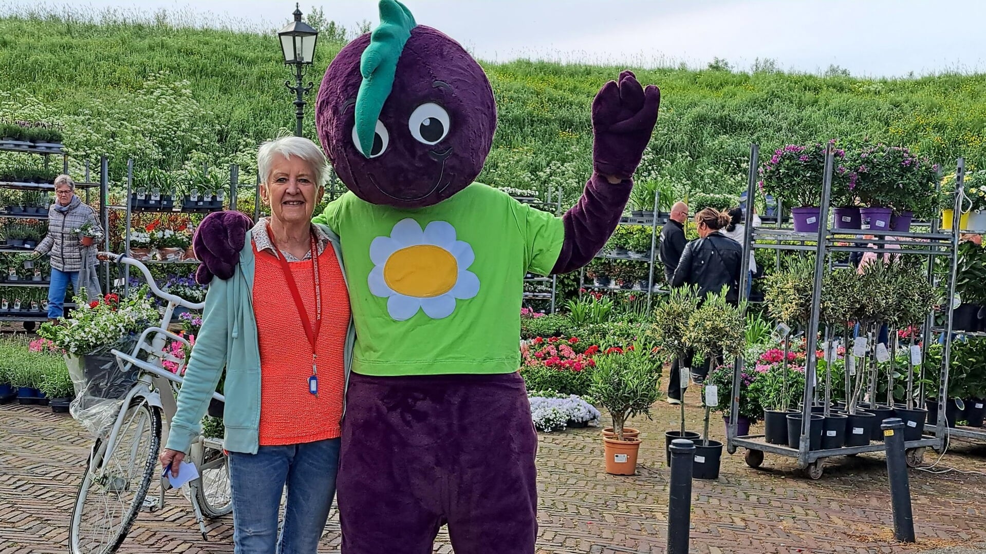 • Vrijwilliger Leni samen met mascotte 'Groentje' op de plantjesmarkt in Vreeswijki.
