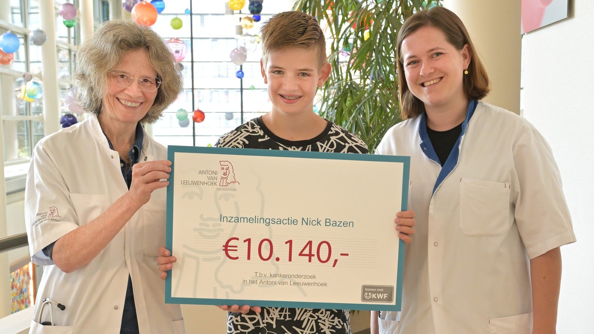 Nick overhandigt de cheque aan artsen van het Antoni van Leeuwenhoek Ziekenhuis.