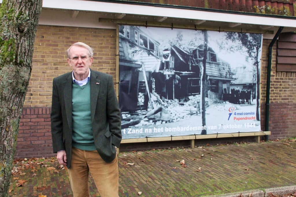 • Wim de Leur bij de onlangs opgehangen foto van het bombardement van 't Zand.