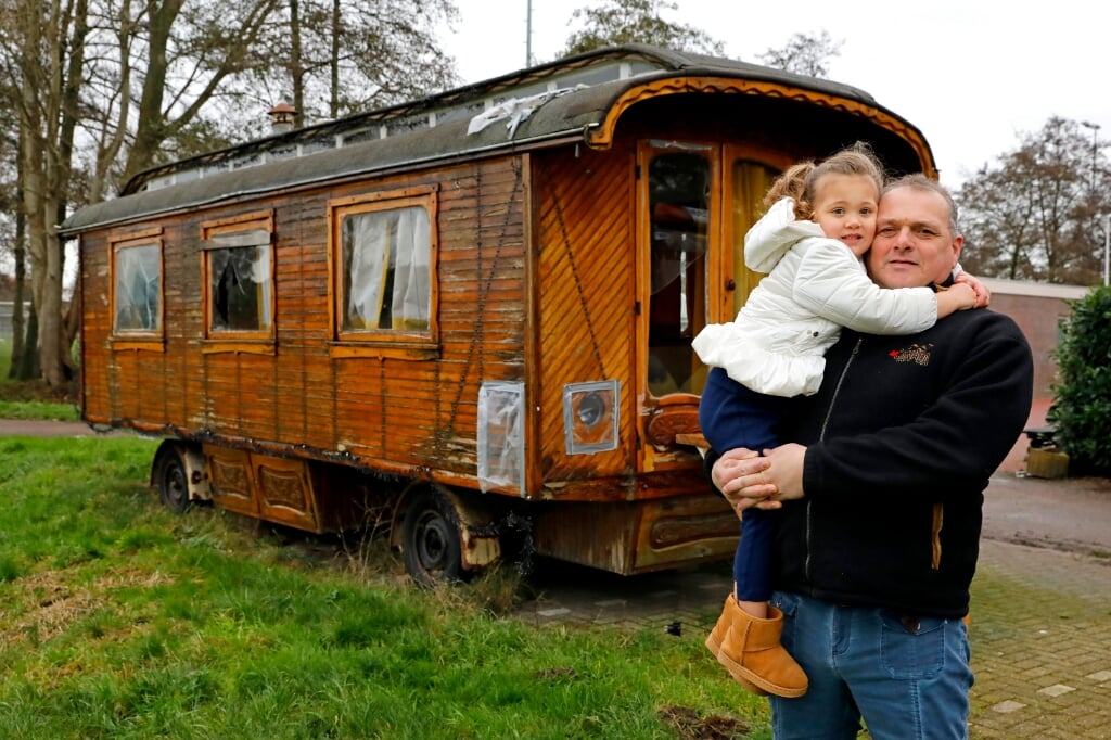 • Piet van Assendorp en zijn kleindochter Sophie voor de 'opknapwoonwagen' aan de ingang van het Arkelse woonwagenkamp.