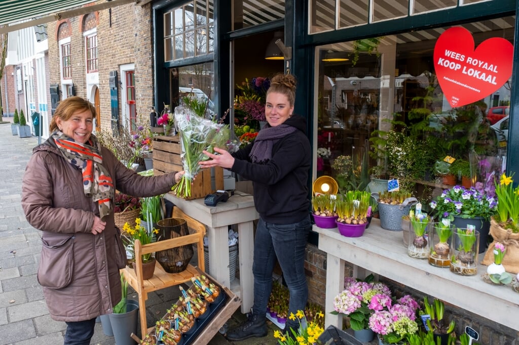• Michelle van den Berg van Bloembinderij Gewoon Natuurlijk overhandigt een klant voor de winkel een bos bloemen.