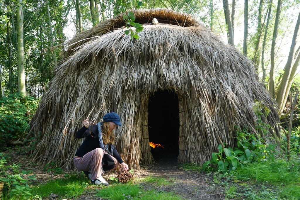 Lucia de Ros aan het werk met riet voor de hut uit de Midden Steentijd, die ze zelf bouwde.