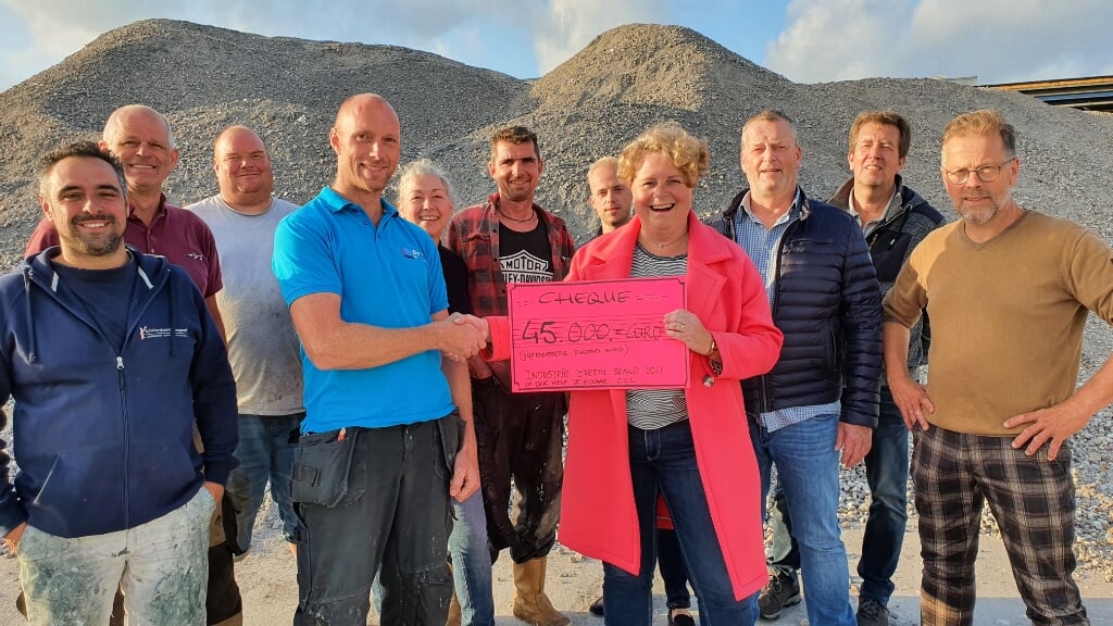 • Met het puin op de  achtergrond reikt Renata de Groot de cheque uit aan Kees-Jan de Haay, één van de door de brand getroffen ondernemers.