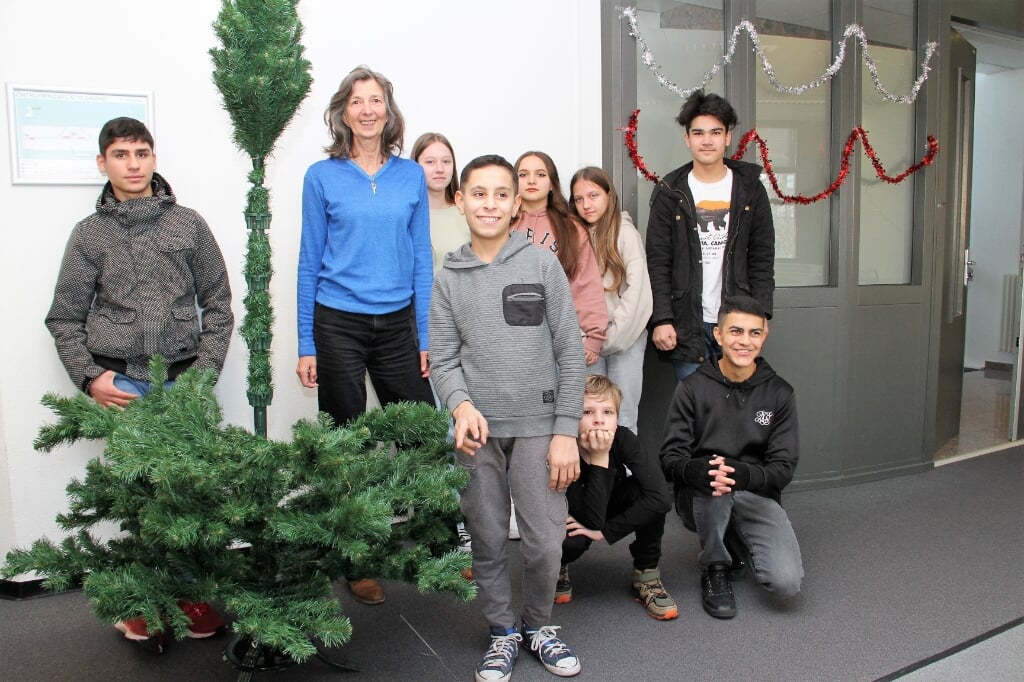 • Karin (blauwe trui) met leerlingen van ISK De Toekomst in Gorinchem, naast de schoolkerstboom in opbouw.