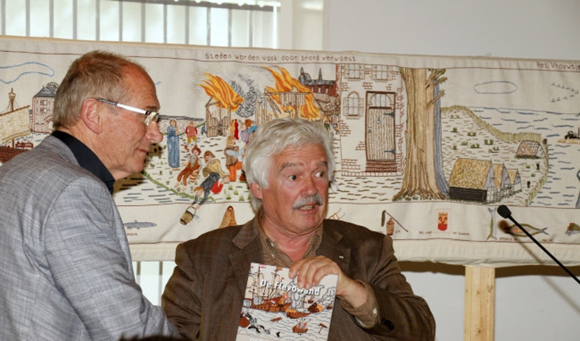  Voorzitter Gert Jan van Tilburg (links) ontvangt een exemplaar van het boek van de uitgever.