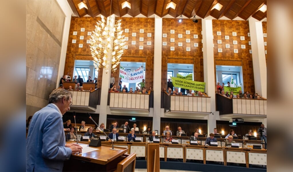  Coos Paulusma spreekt de leden van Provinciale Staten toe onder toeziend oog van een afgeladen tribune met tegenstanders van laagvliegroutes.