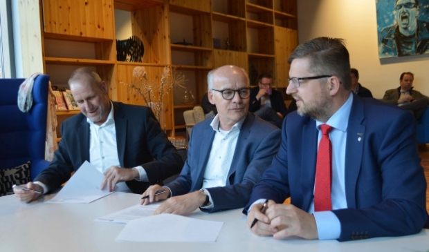 Wethouder Siepel (rechts) bij het plaatsen van de handtekeningen met de aannemers.