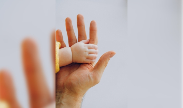 Handje van kind om vinger van ouder.