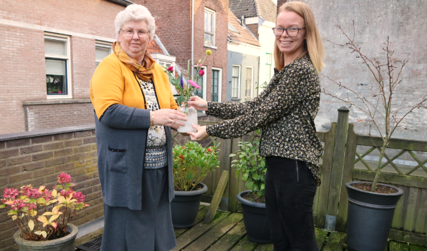 <p>Mevrouw Kroneman ontvangt een bloemetje van Gerla Uilenberg.</p>