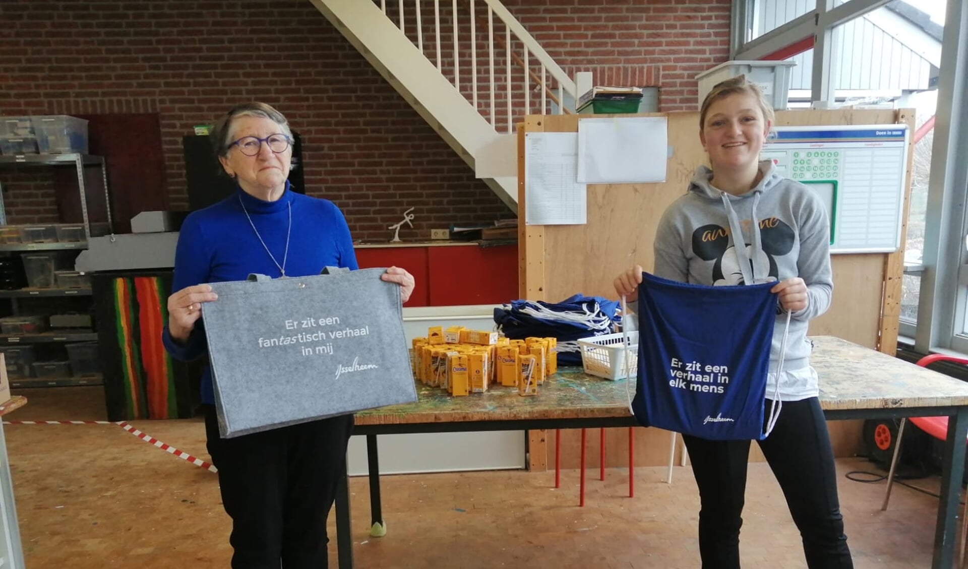 Mevrouw Van den Berg van de cliëntenraad ontvangt de tasjes van Kirsten, leerling van de Spanker.