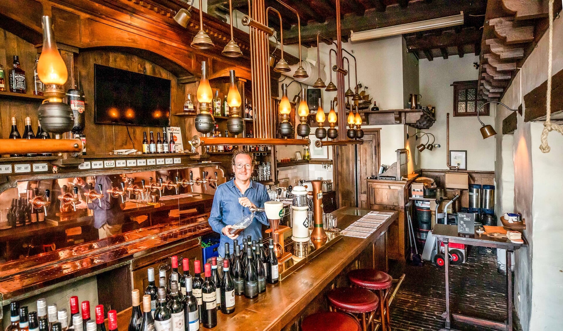 David is een fles met bier aan het vullen om te bezorgen aan een klant. Nu ze niet meer aan de bar gedronken kunnen worden, bezorgt hij ze.