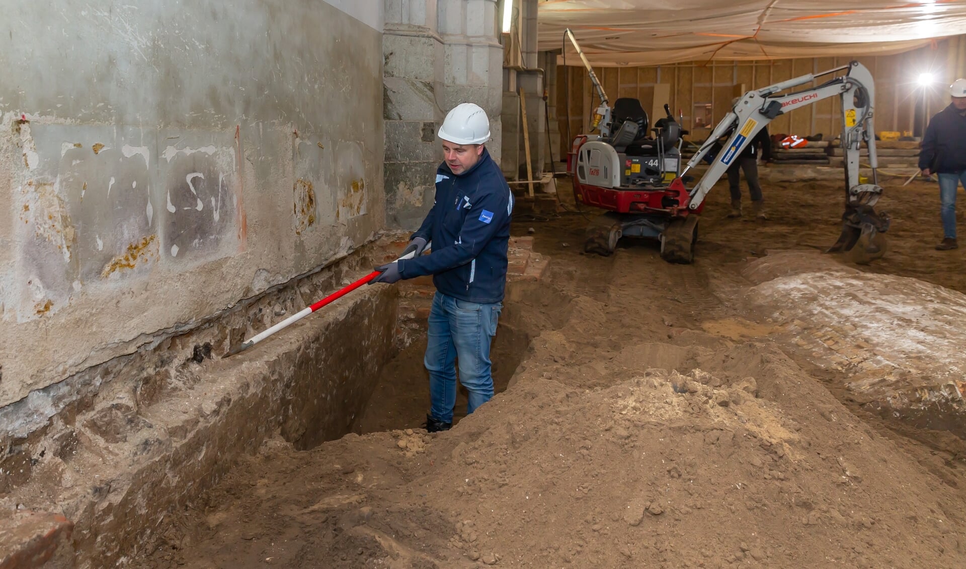 Stadsarcheoloog Michael Klomp bij de oude muur die gevonden werd. Rechts de gevonden grafkelder van de familie Haersoltes.