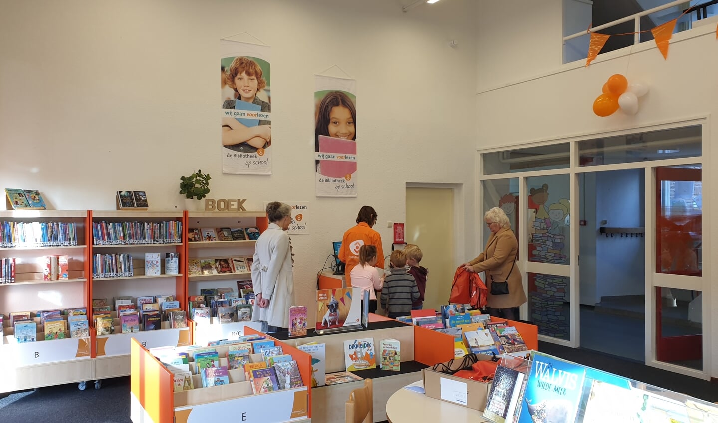 Leesconsulent Marjan Albert en de 2 bibliotheekoma's van het Visnet helpen leerlingen bij het lenen van hun eerste boek uit de nieuwe schoolbibliotheek.
