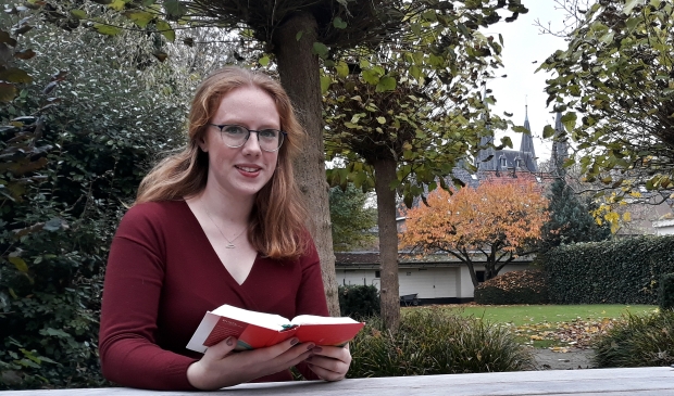 <p>Maaike Messelink leest de Bijbel in de tuin van de TUK</p>