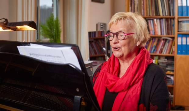 <p>Jenny van Ark thuis zingend achter de piano.</p>