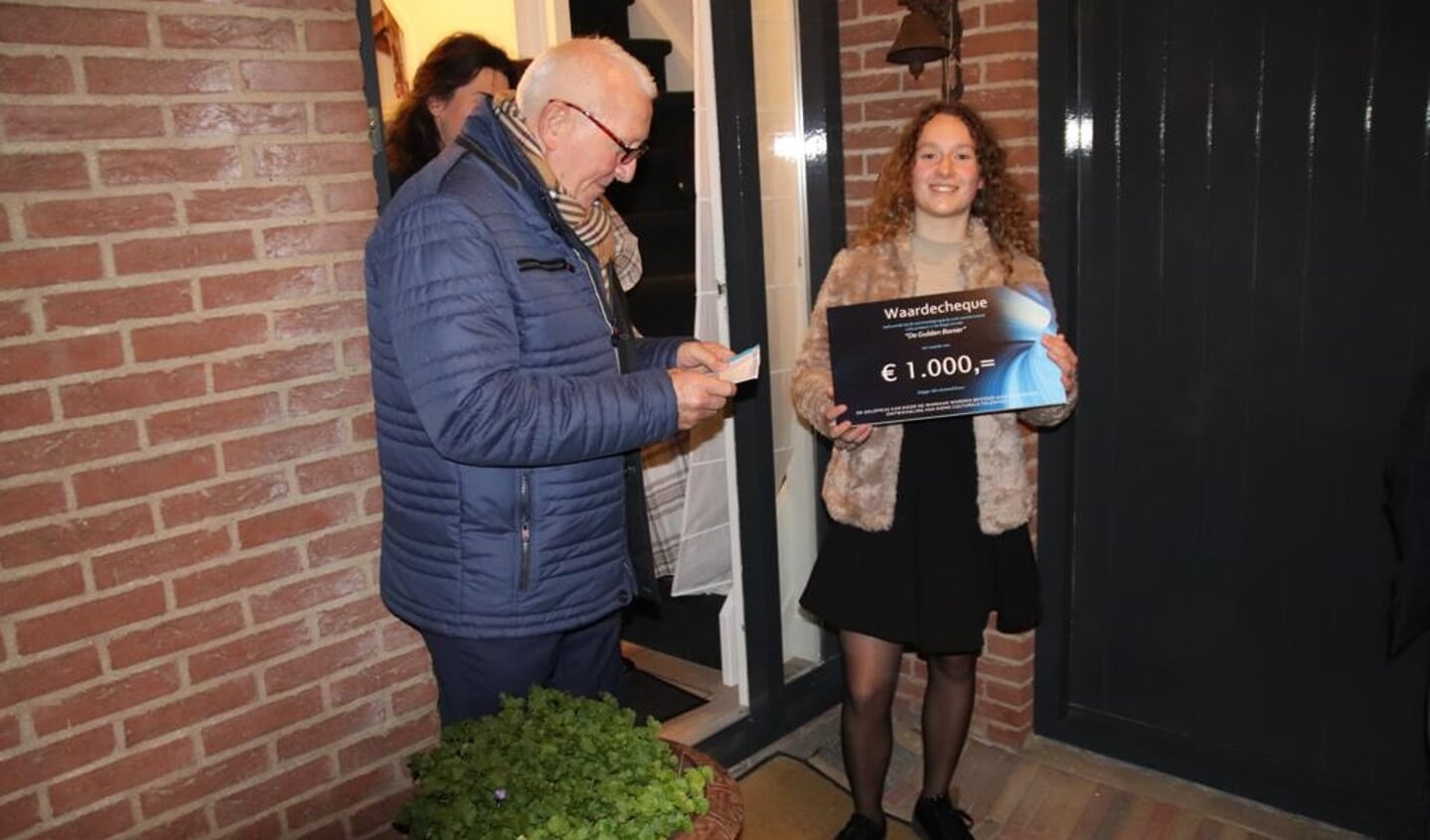 Bestuurslid van Stichting De Banier Hans van Berkum spreekt de winnares van de aanmoedigingsprijs De Gulden Banier 2021 Raïsa Ploeg toe. Op de achtergrond kijkt de trotse moeder toe.