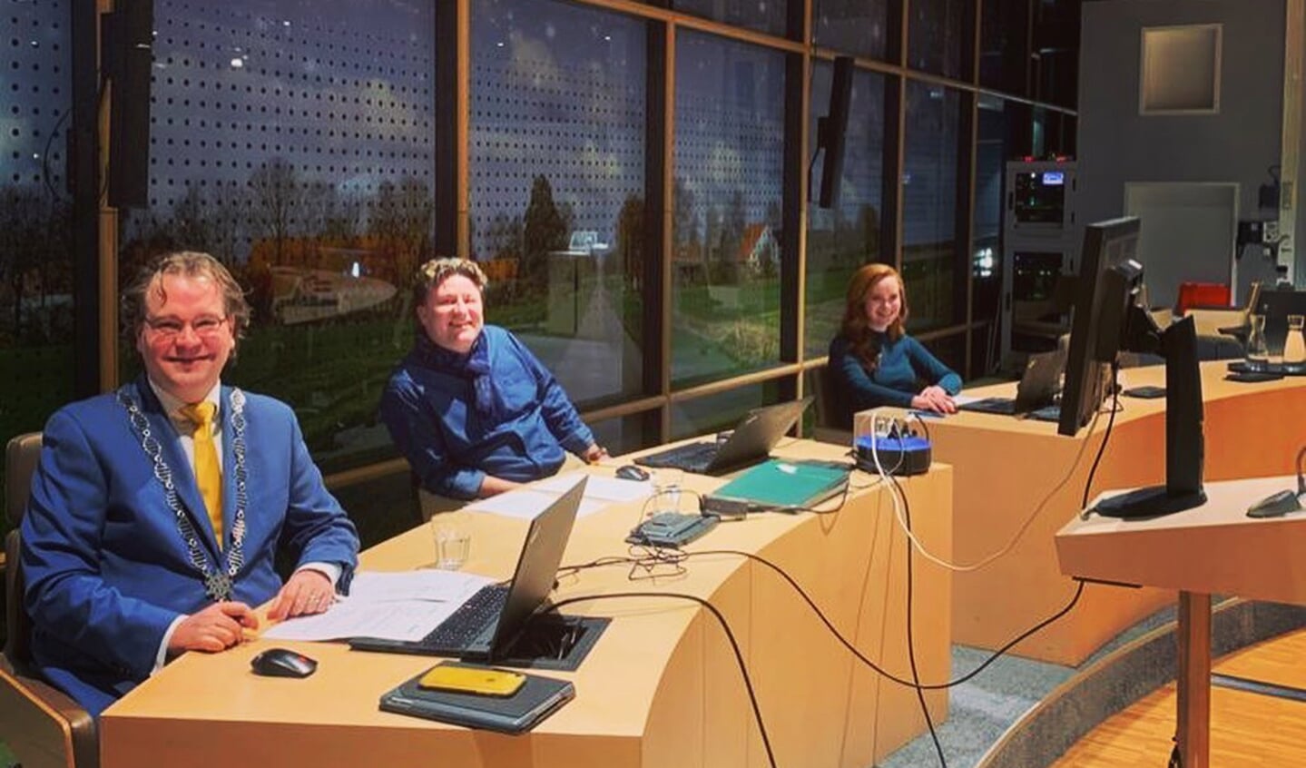 Paul Vermast (li.) en medewerkers van de griffie in een verder lege raadszaal.