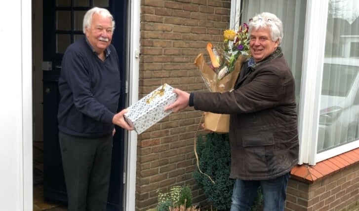 Ton ter Bekke (links) ontvangt uit handen van voorzitter Rinke Beverwijk een bos bloemen en een kistje wijn.