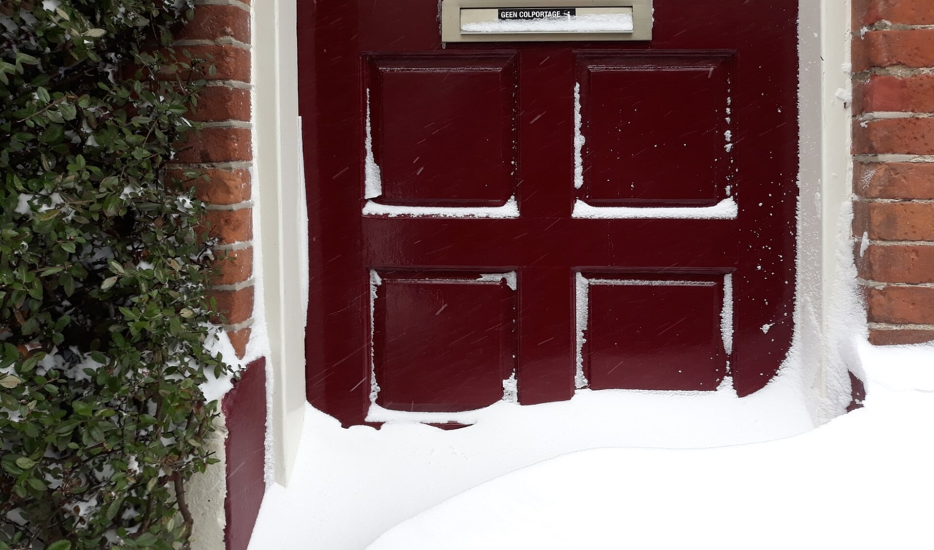 Sneeuwduin tegen de voordeur.
