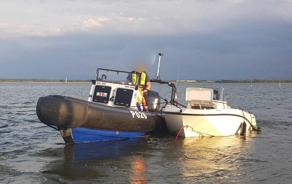 De speedboot wordt door de politie naar de kant gebracht.
