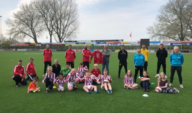 <p>Jan Bouwmeester (m) showt het nieuwe trainerspak voor de Happy Kidz-trainers.</p>