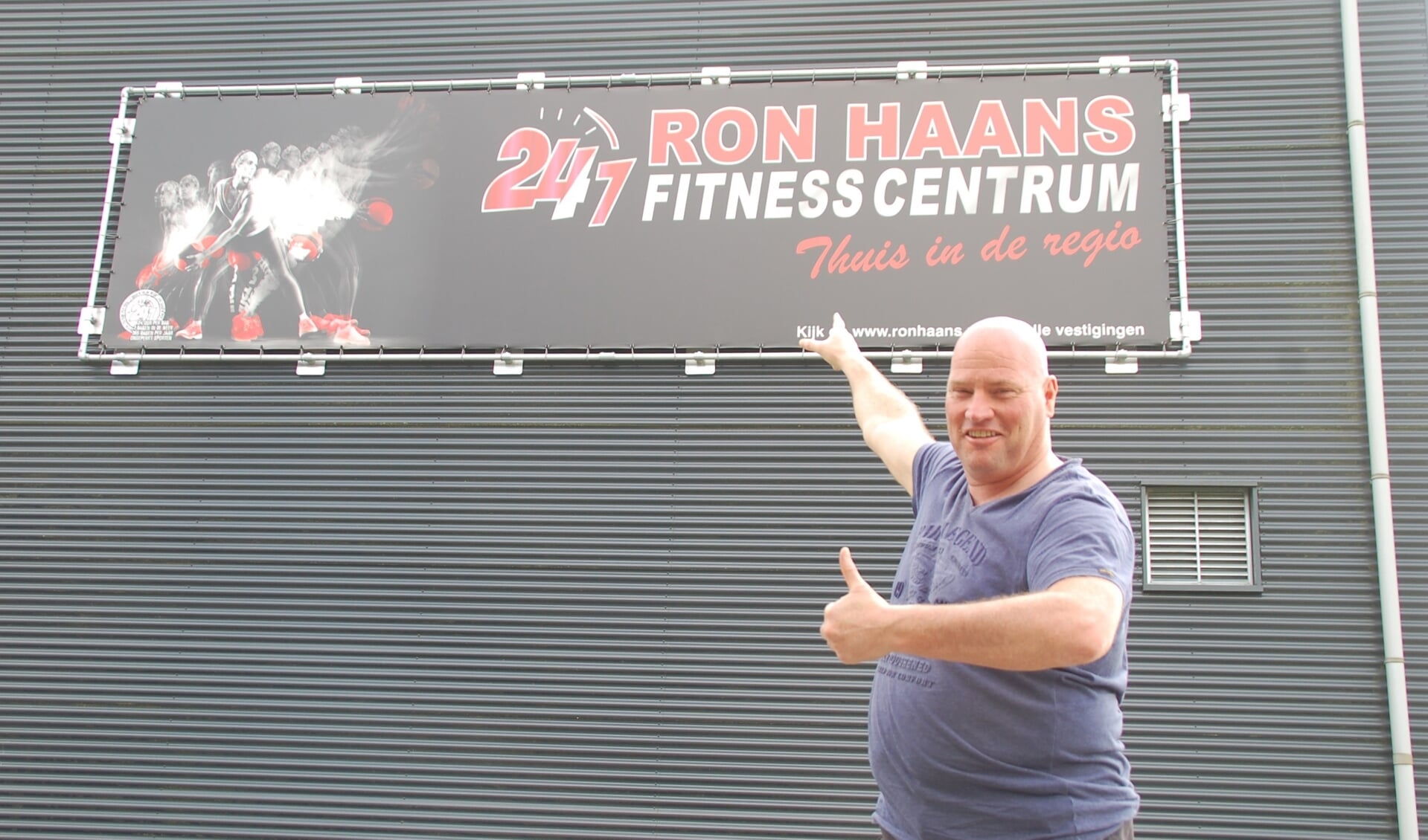 Ron Haans bij het bord van zijn nieuwe sportschool. 