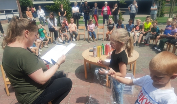 Twee leerlingen van De Fontein overhandigen het eerste exemplaar van de verhalenbundel
