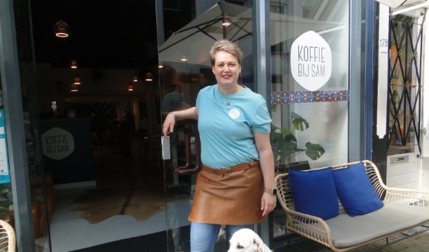 Op de foto: Sam en de hond Boyd voor de ingang van Koffie bij Sam