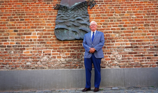 <p> Arie van Driesten met op de achtergrond het herdenkingsmonument op de Markt.</p>