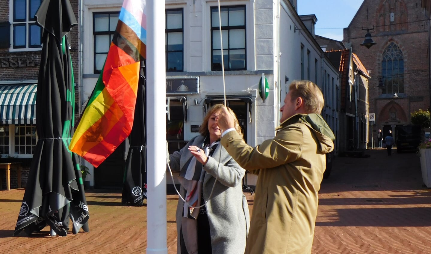 Wethouder Trijn Jongman en burgemeester Rob Bats hijsen samen de regenboogvlag