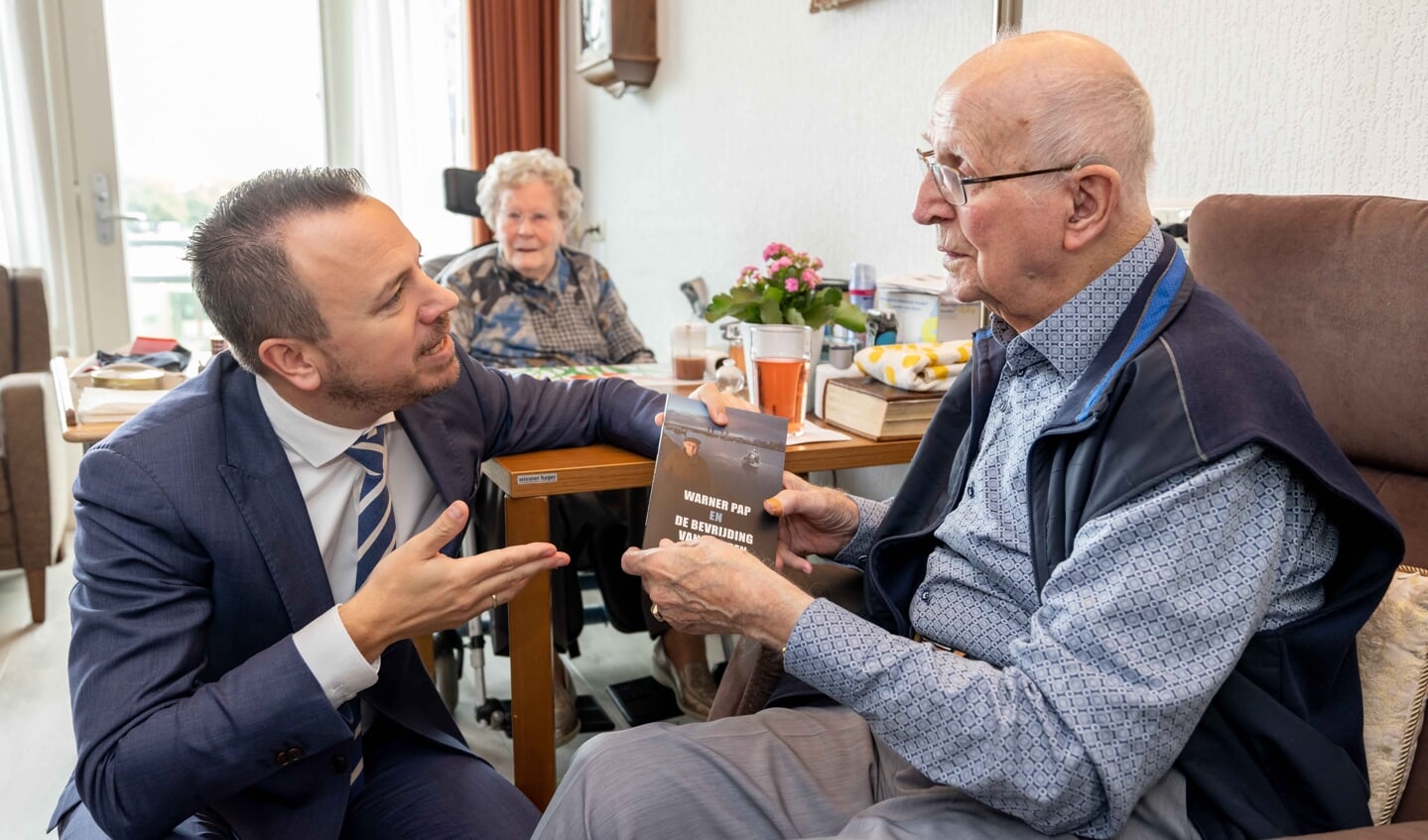 Foto: Warner Pap overhandigt het eerste exemplaar van het boek aan de burgemeester.