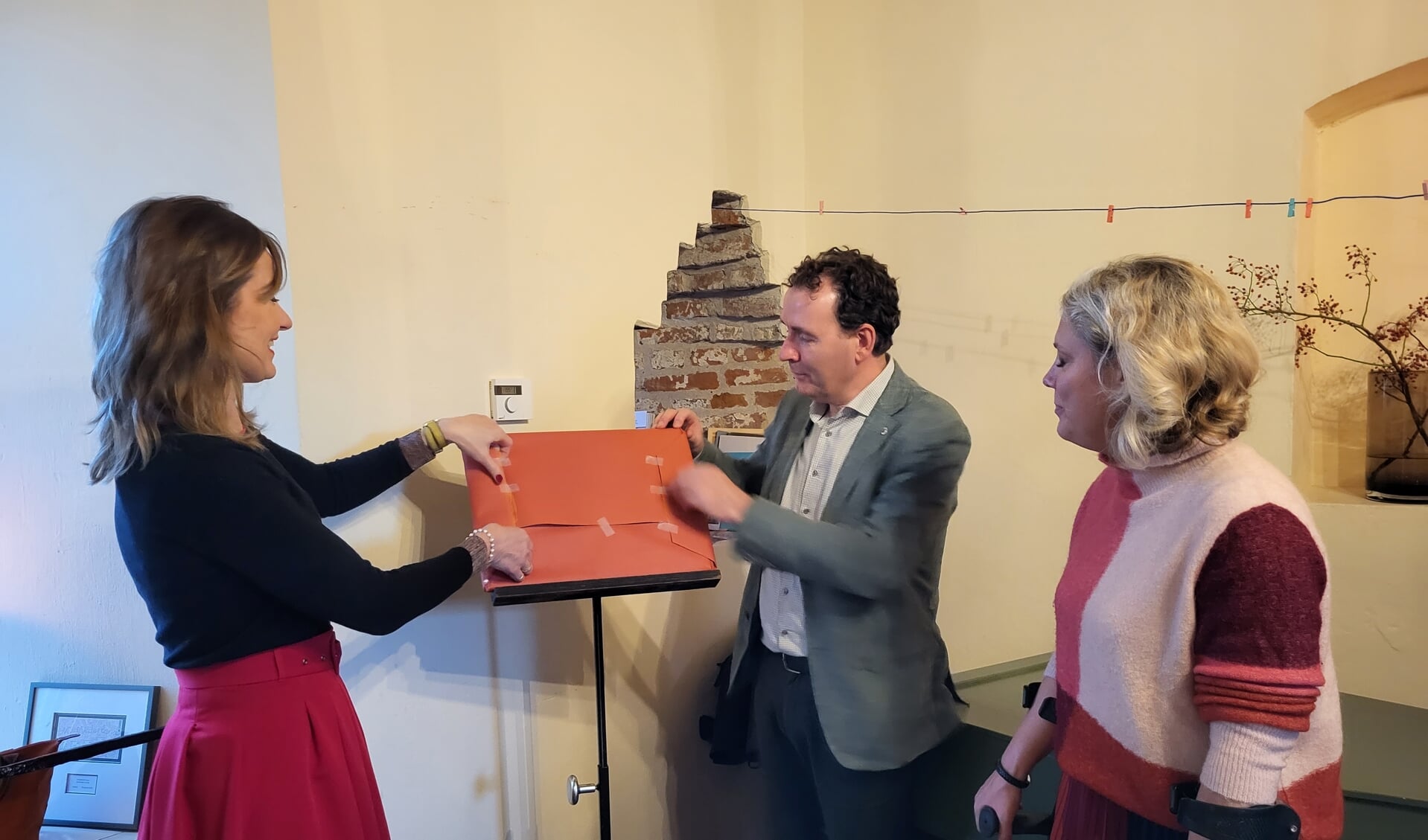 Edith de Jong, Lions president Sven van Helden en burgemeester Sanderse onthulden in de Dijkpoort het eerste exemplaar van de nieuwe zeefdruk van Hattem.