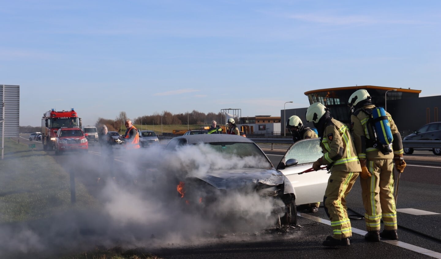 De brandweer blust de autobrand