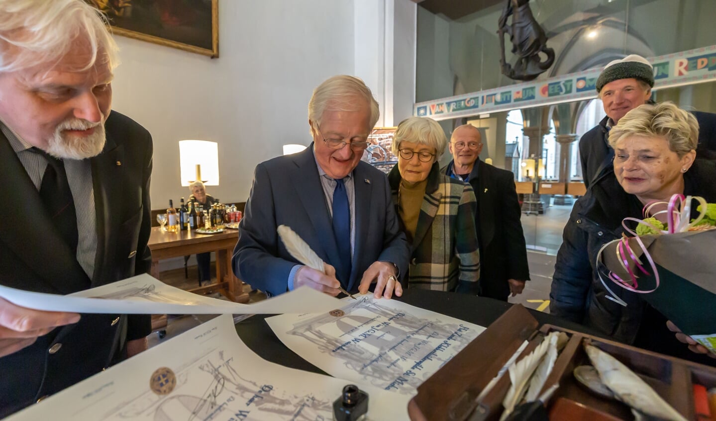 Wim Waanders ondertekent toeziend oog van zijn echtgenote zijn aanstelling tot beschermheer van het klokkenluidersgilde Zwolle.