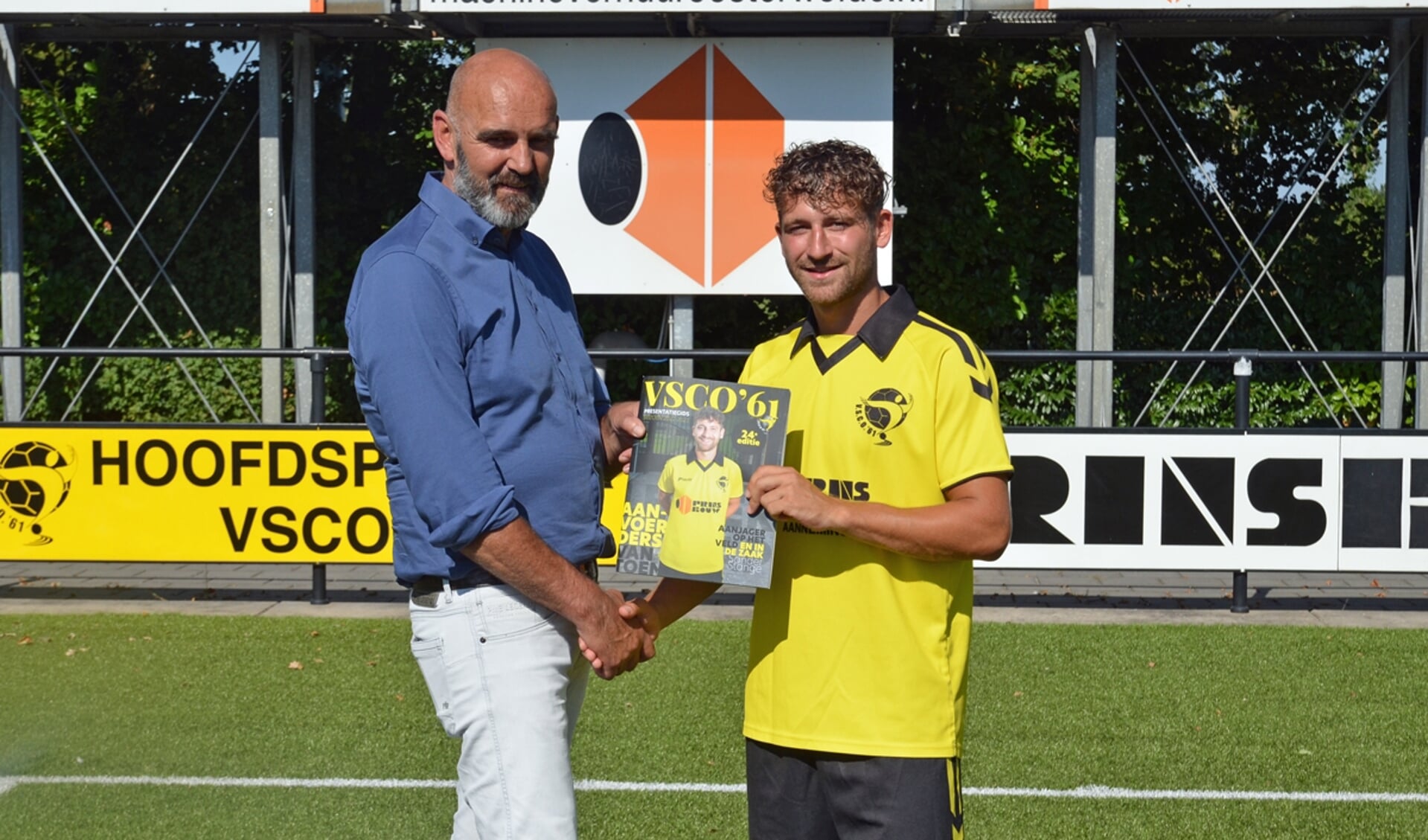 Wethouder van sport van de gemeente Oldebroek, Beerd Flier, neemt het eerste exemplaar van de presentatiegids in ontvangst van selectiespeler Sander Stange, die op de cover staat.