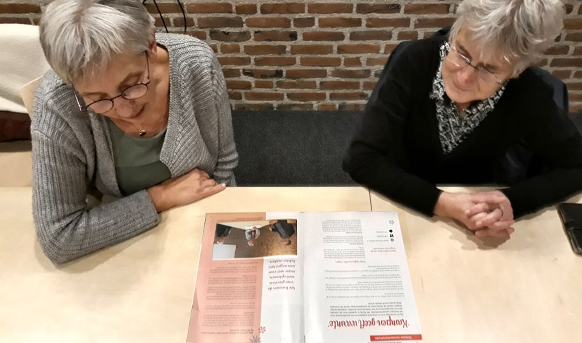 Marijke van Raalte en Joke Luiten lezen een artikel over het fonds in het kerkblad Mozaïek