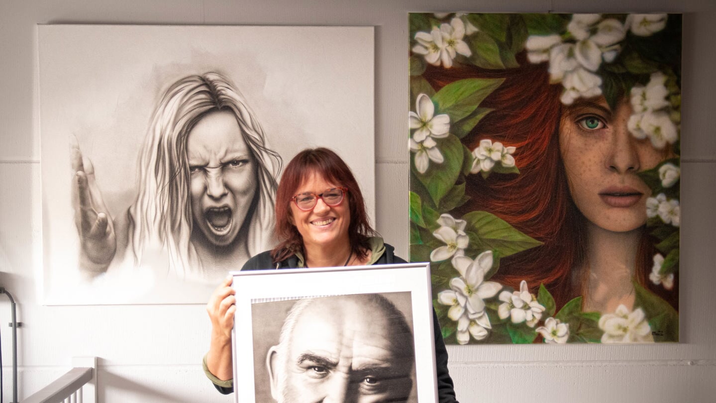 Marcia Timmermans-IJzerman met drie van haar airbrushschilderijen 