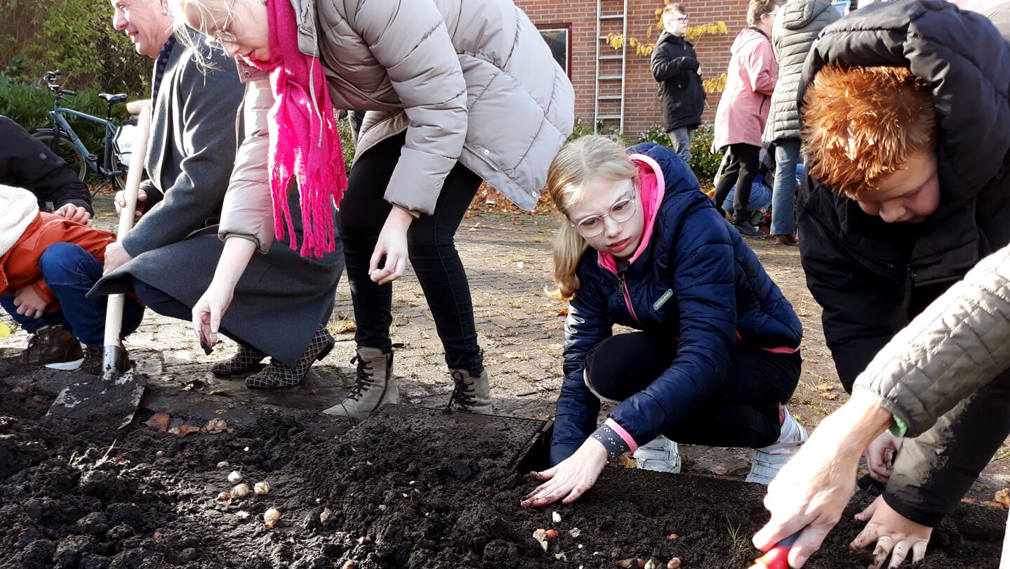 Wethouder Faber (links) steekt de schop in de grond voor de boomaanplant