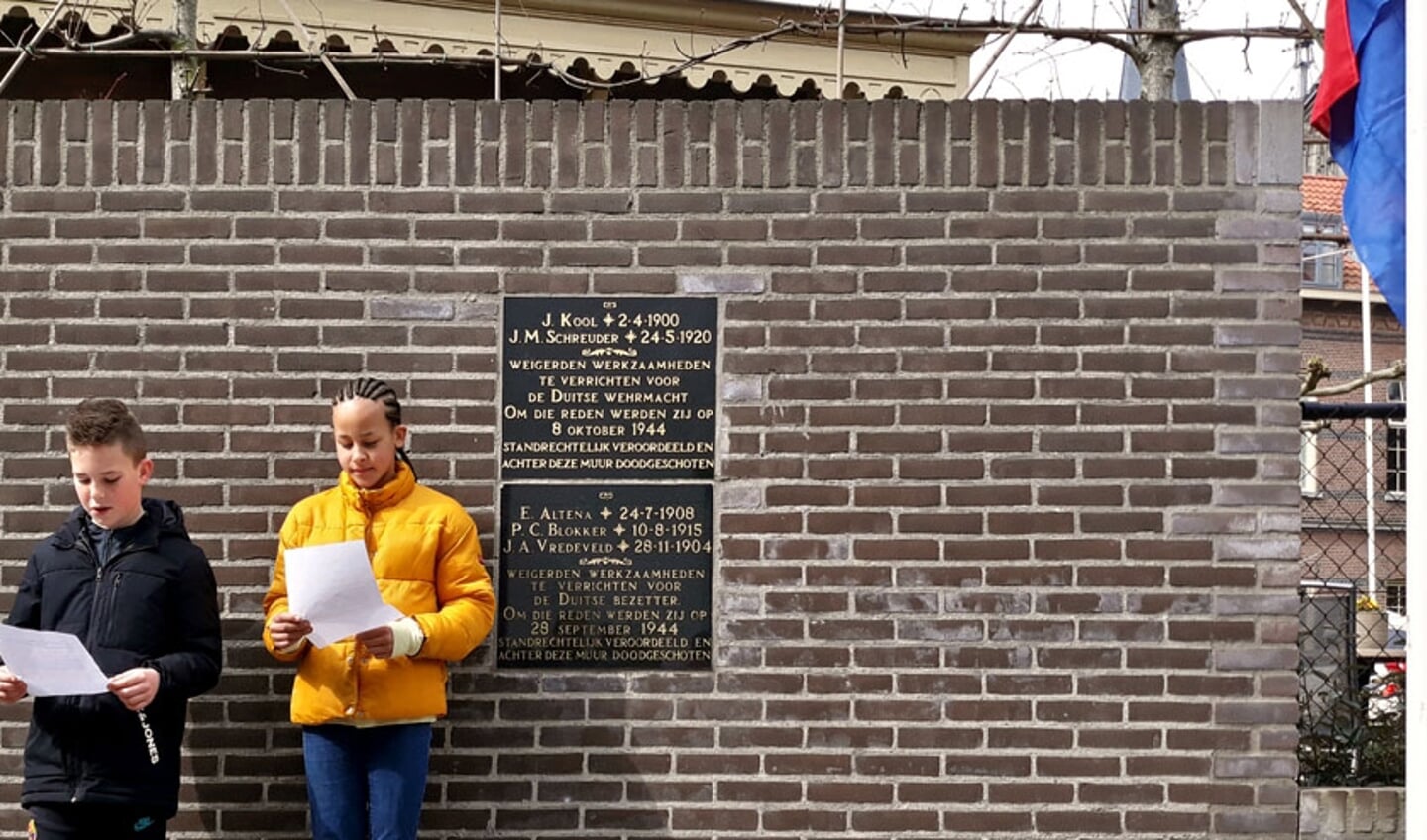 Twee leerlingen houden een voordracht bij het oorlogsmonument aan de Prinsenstraat