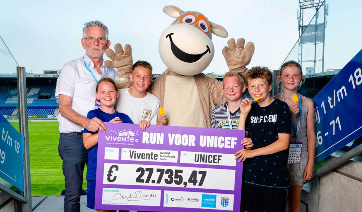 Arend Eilander met leerlingen van Vivente en de cheque van 27735,47 voor UNICEF 