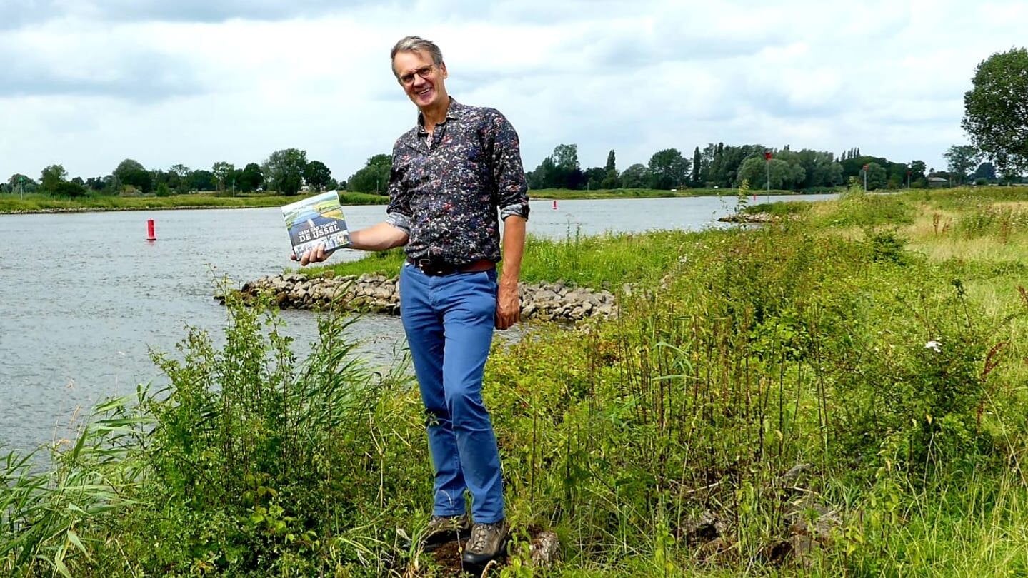 Wim Eikelboom met zijn boek bij de IJssel.