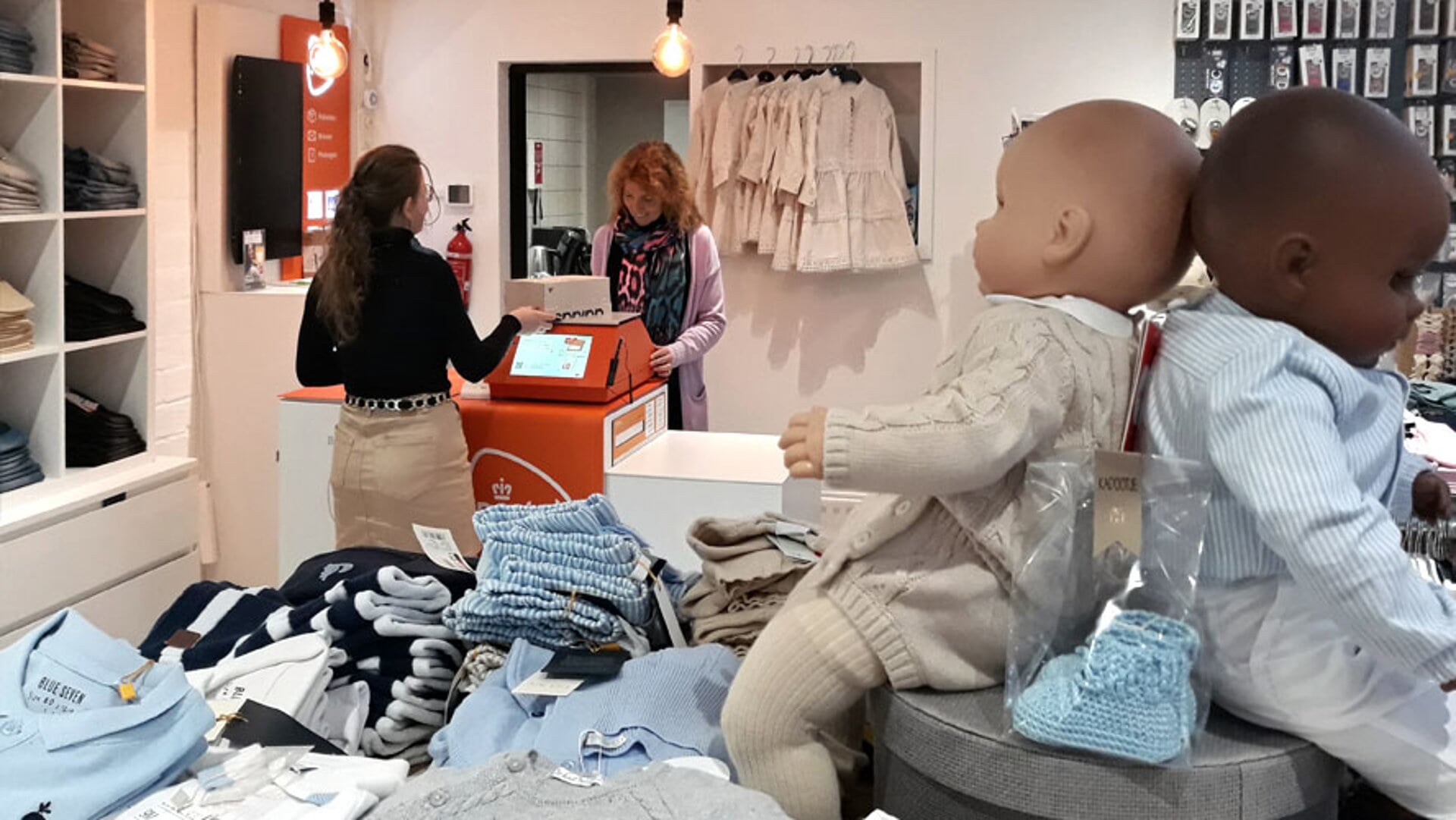 Blik in de kledingzaak in IJsselmuiden met het afhaalpunt van PostNL op de achtergrond