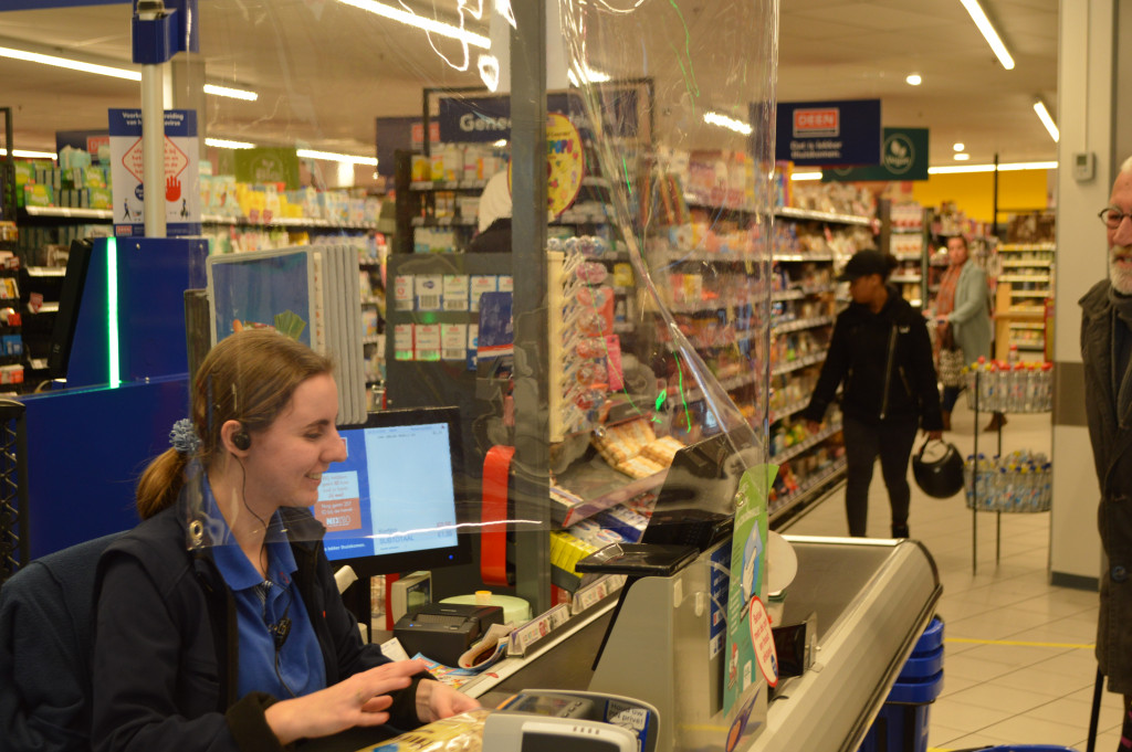 Cassière achter plastic scherm bij Deen.