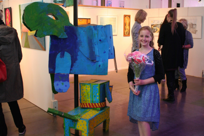 Lotte volgt de cursus Kinderkunst en staat naast haar kartonkunstbeest.